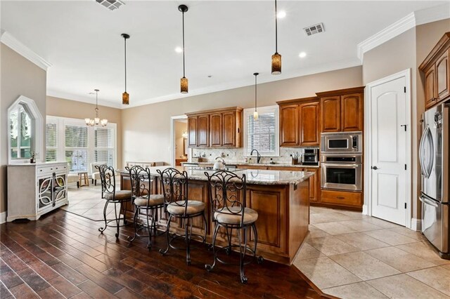 kitchen featuring sink, stainless steel oven, hanging light fixtures, light stone countertops, and decorative backsplash