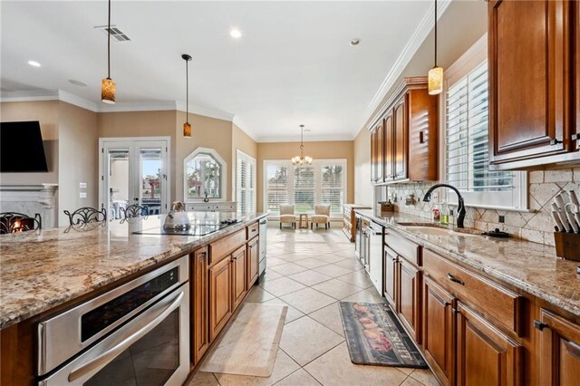 kitchen featuring decorative light fixtures, light stone countertops, sink, oven, and decorative backsplash