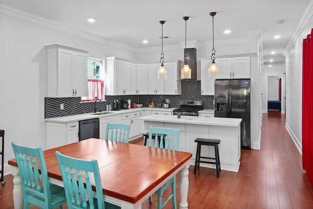 kitchen featuring a center island, sink, wall chimney range hood, decorative light fixtures, and black appliances