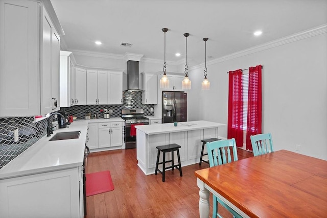 1519-21 N Villere St, New Orleans, LA 70116 - kitchen with appliances with stainless steel finishes, wall chimney exhaust hood, a center island, backsplash, and white cabinetry