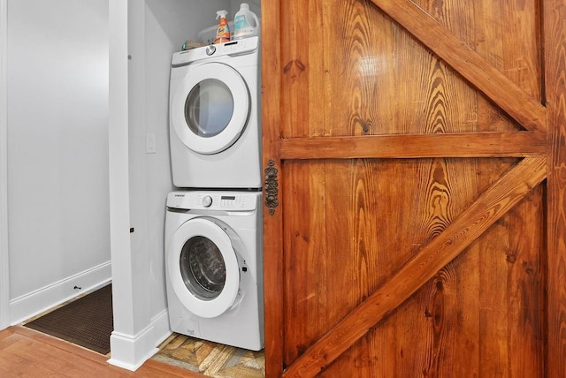 laundry room with wood-type flooring and stacked washing maching and dryer