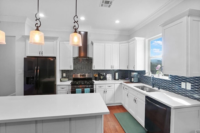 kitchen with white cabinets, pendant lighting, wall chimney exhaust hood, and black appliances