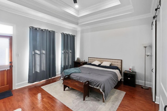 bedroom featuring dark hardwood / wood-style floors, a tray ceiling, crown molding, and ceiling fan