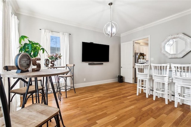 dining space with ornamental molding, light wood-type flooring, and a notable chandelier