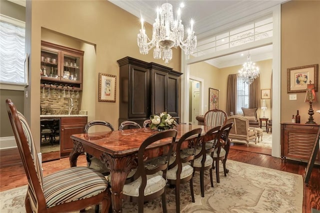 dining space featuring hardwood / wood-style floors, wine cooler, an inviting chandelier, and ornamental molding