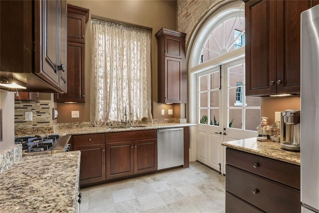 kitchen featuring dark brown cabinets, stainless steel appliances, light stone counters, and sink