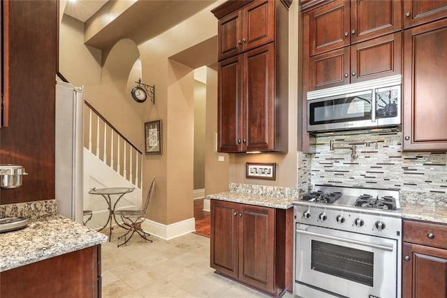 kitchen with decorative backsplash, stainless steel appliances, and light stone countertops