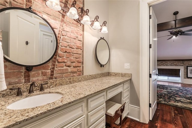 bathroom featuring ceiling fan, vanity, brick wall, and wood-type flooring