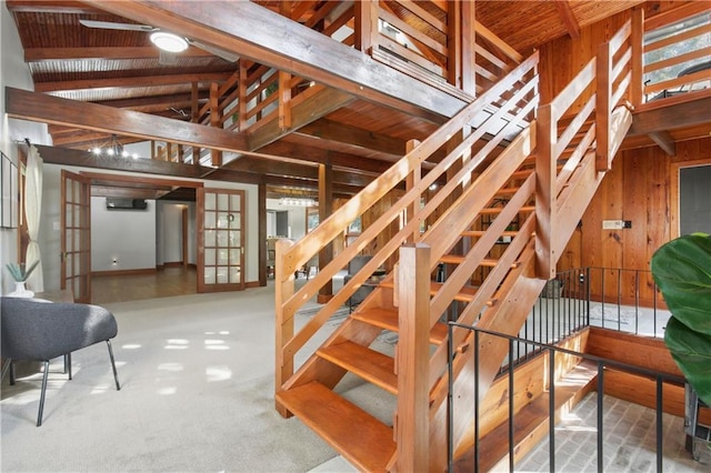 stairway featuring wood walls, french doors, carpet flooring, vaulted ceiling with beams, and wood ceiling