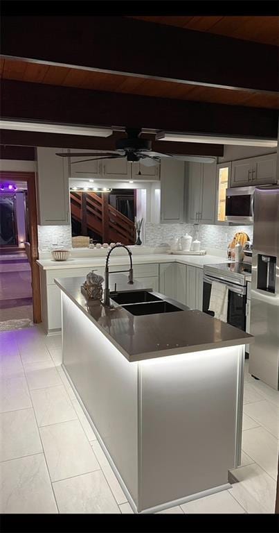 kitchen with a center island with sink, decorative backsplash, ceiling fan, light tile patterned floors, and stainless steel appliances