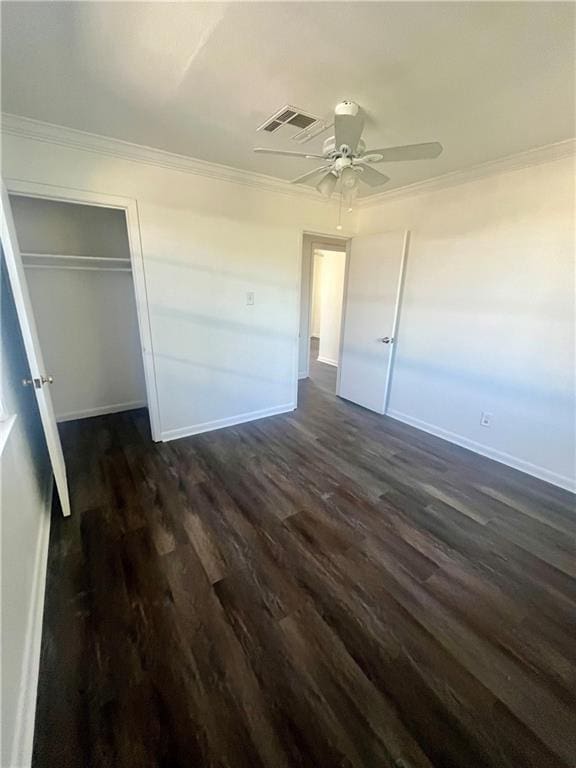 unfurnished bedroom featuring ceiling fan, dark hardwood / wood-style floors, crown molding, and a closet