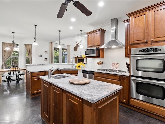 kitchen featuring wall chimney range hood, an island with sink, and a wealth of natural light