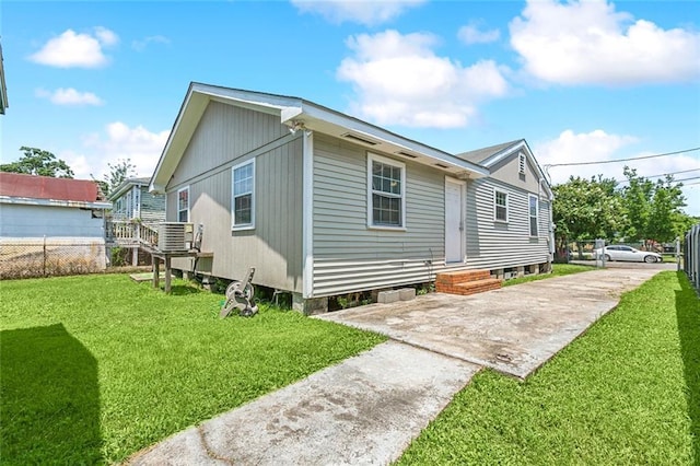 rear view of house featuring central AC unit and a yard