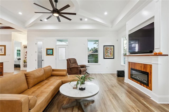 living room featuring beam ceiling, ceiling fan, a healthy amount of sunlight, and light wood-type flooring