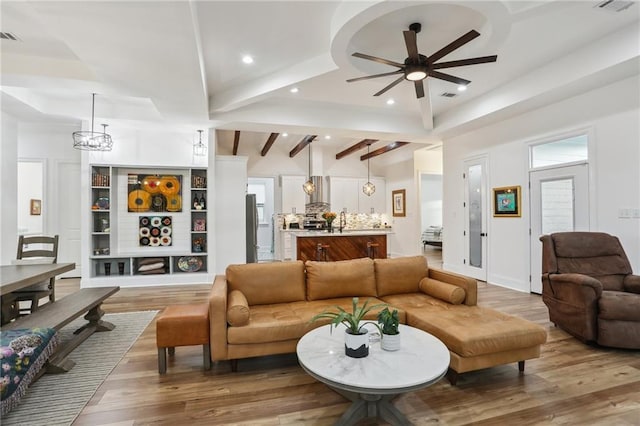 living room with ceiling fan with notable chandelier, lofted ceiling with beams, and wood-type flooring