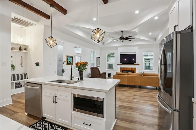 kitchen featuring sink, white cabinets, decorative light fixtures, and appliances with stainless steel finishes