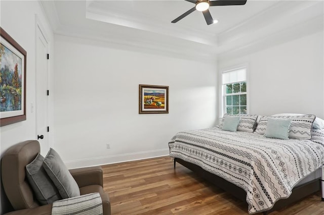 bedroom featuring a tray ceiling, ceiling fan, dark hardwood / wood-style flooring, and ornamental molding