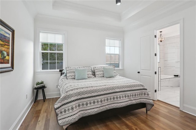 bedroom featuring hardwood / wood-style floors, connected bathroom, an inviting chandelier, and crown molding