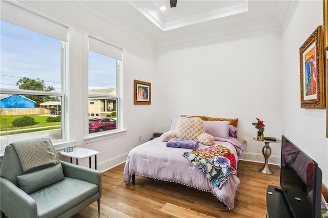 bedroom with hardwood / wood-style floors, a raised ceiling, ceiling fan, and ornamental molding