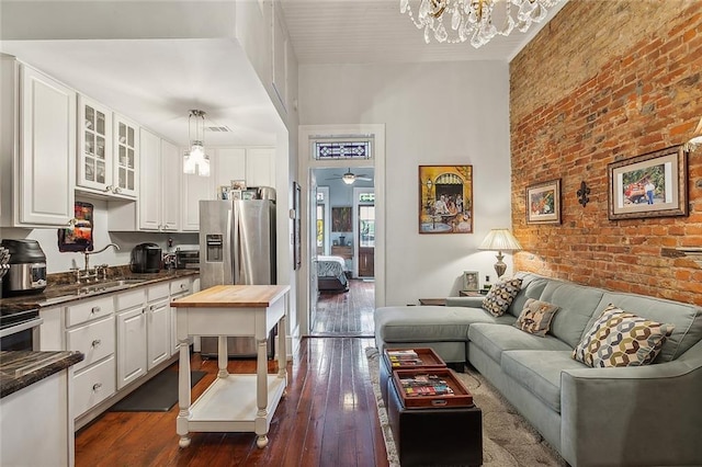 kitchen with white cabinets, dark hardwood / wood-style floors, hanging light fixtures, and brick wall