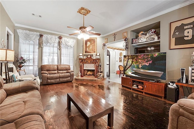 living room featuring a fireplace, hardwood / wood-style floors, ceiling fan, and crown molding