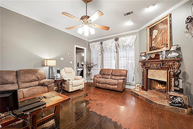 living room with a tile fireplace, crown molding, dark hardwood / wood-style flooring, and ceiling fan