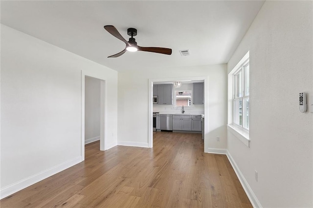 unfurnished living room with ceiling fan, sink, and light hardwood / wood-style flooring