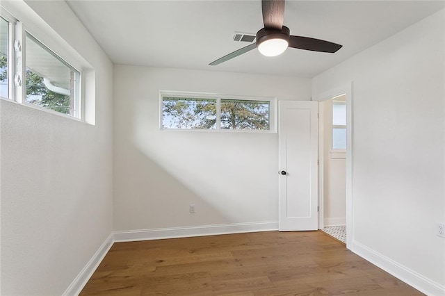 spare room with a wealth of natural light, ceiling fan, and hardwood / wood-style flooring