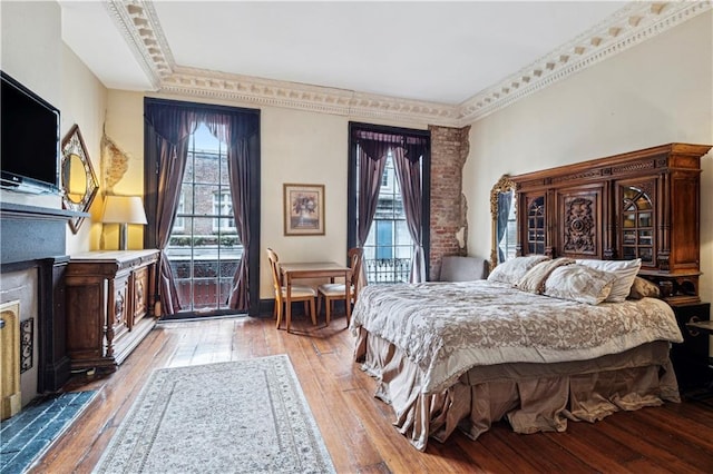 bedroom with a fireplace, light hardwood / wood-style flooring, and crown molding