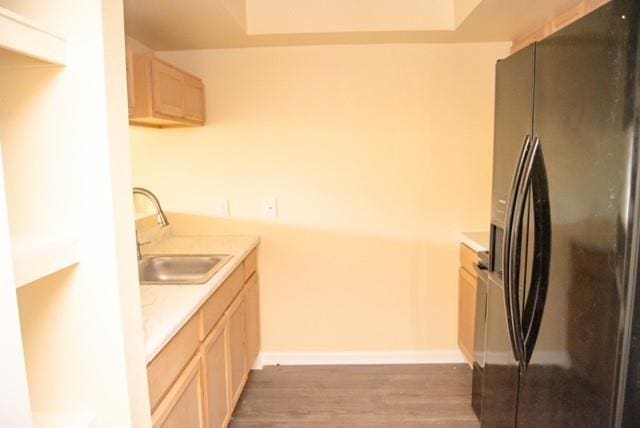 kitchen with hardwood / wood-style floors, light brown cabinetry, black refrigerator with ice dispenser, and sink