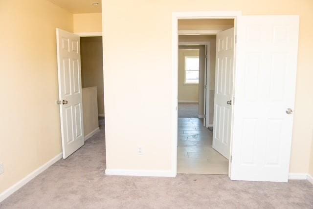 unfurnished bedroom featuring a closet and light colored carpet