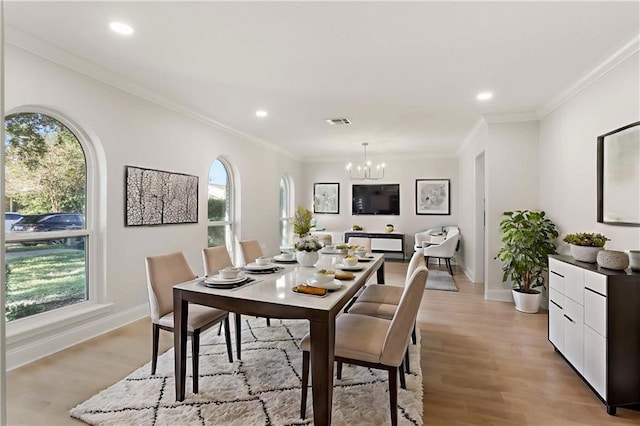 dining area featuring an inviting chandelier, ornamental molding, and light hardwood / wood-style flooring