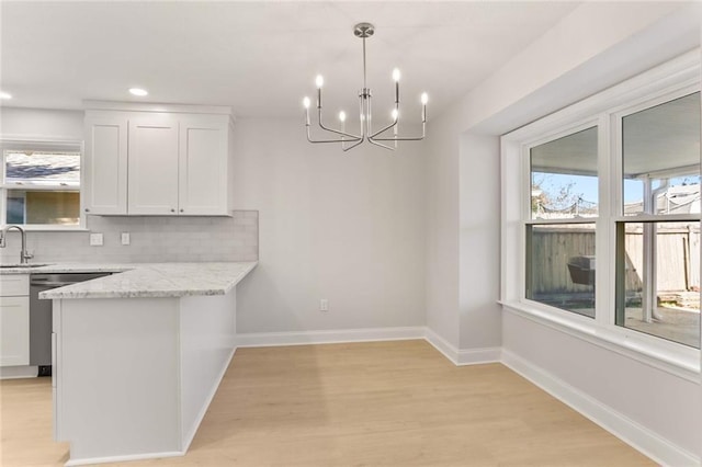 kitchen featuring hanging light fixtures, light wood-type flooring, tasteful backsplash, light stone counters, and white cabinetry