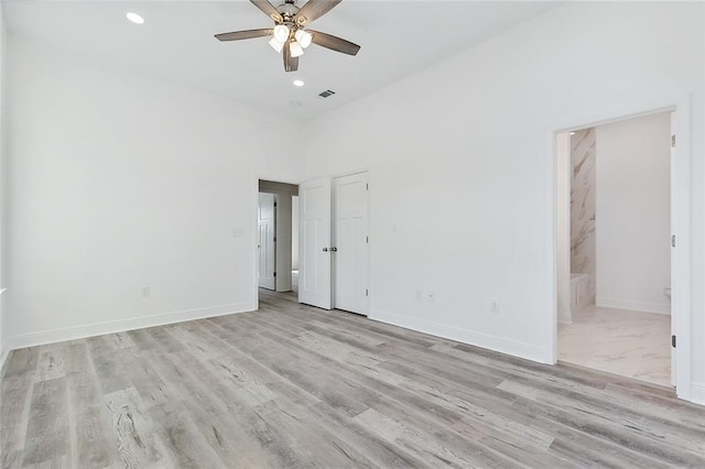 empty room featuring ceiling fan, light hardwood / wood-style floors, and a high ceiling