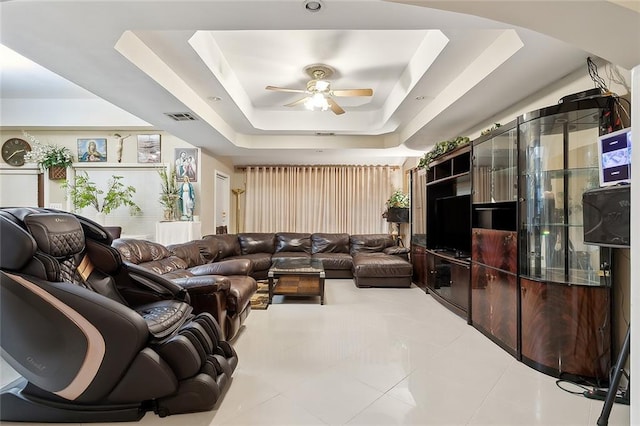 tiled living room featuring a tray ceiling and ceiling fan