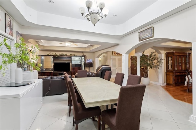 dining room featuring a tray ceiling, light tile patterned floors, and ceiling fan with notable chandelier