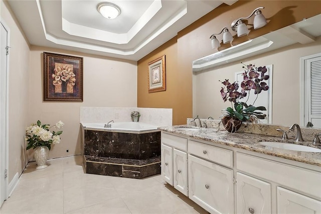 bathroom featuring a tray ceiling, tiled tub, tile patterned flooring, and vanity