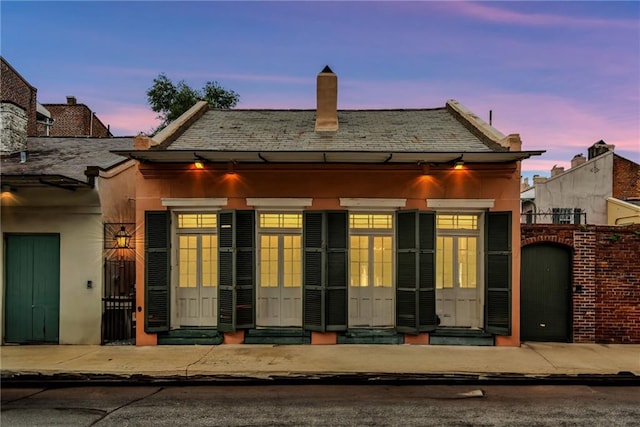 625 Dumaine St, New Orleans, LA 70116 - view of front facade with a gate, stucco siding, a chimney, entry steps, and a high end roof