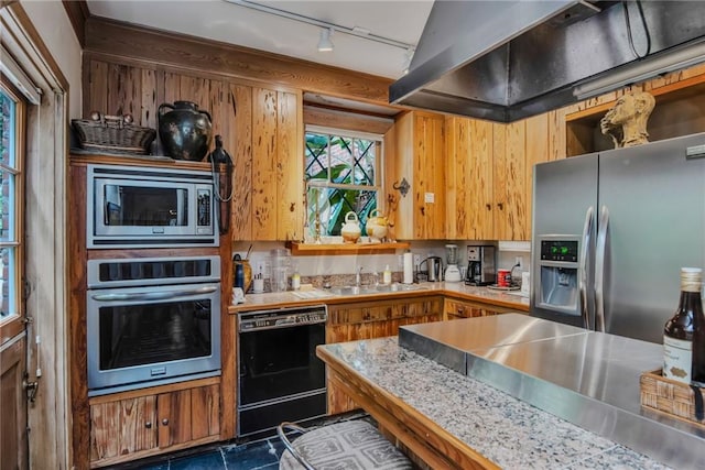 625 Dumaine St, New Orleans, LA 70116 - kitchen with appliances with stainless steel finishes, exhaust hood, track lighting, light countertops, and brown cabinets