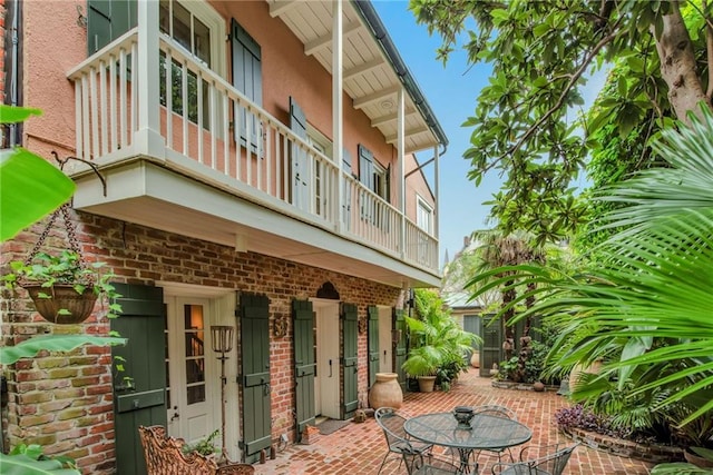 625 Dumaine St, New Orleans, LA 70116 - view of home's exterior featuring a balcony, a patio, stucco siding, and brick siding