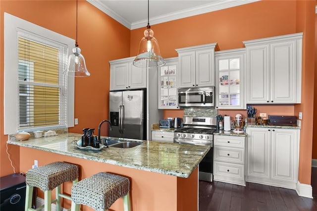 kitchen featuring decorative light fixtures, kitchen peninsula, crown molding, white cabinetry, and appliances with stainless steel finishes