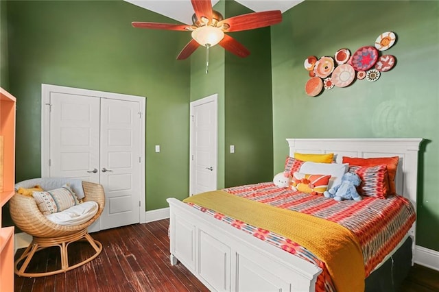 bedroom featuring ceiling fan, a closet, dark hardwood / wood-style floors, and a towering ceiling