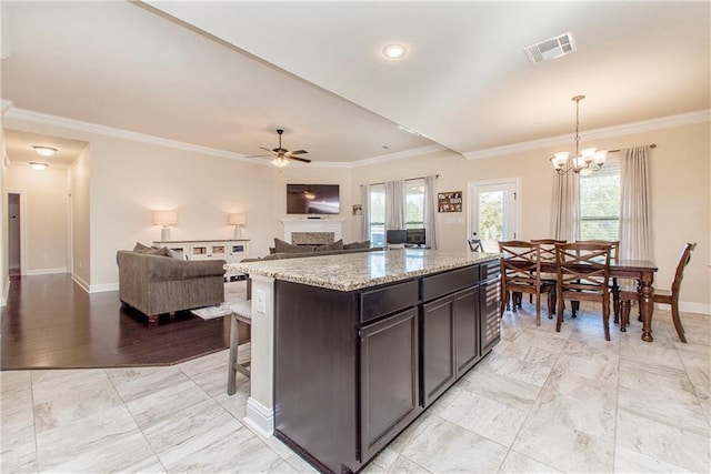 kitchen with a center island, hanging light fixtures, crown molding, dark brown cabinets, and ceiling fan with notable chandelier