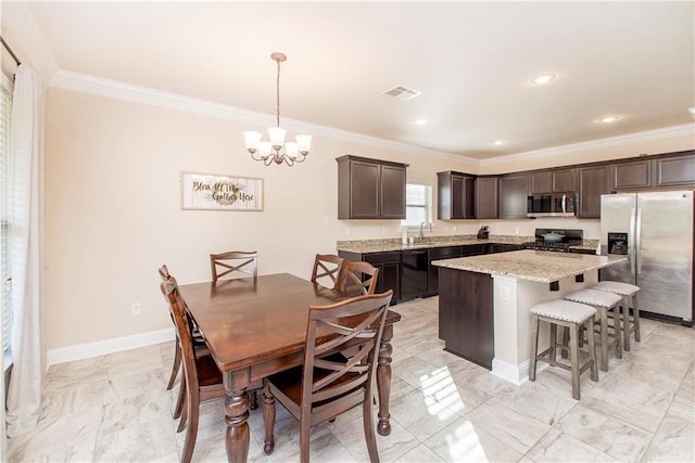 kitchen with hanging light fixtures, a kitchen island, stainless steel appliances, and ornamental molding