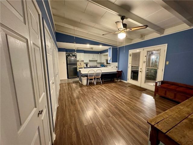 kitchen with dark wood-type flooring, lofted ceiling with beams, ceiling fan, white cabinetry, and stainless steel refrigerator