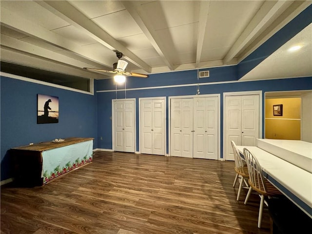 bedroom featuring dark hardwood / wood-style floors, beam ceiling, ceiling fan, and two closets