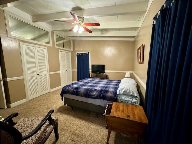 bedroom featuring carpet flooring, ceiling fan, lofted ceiling with beams, and two closets