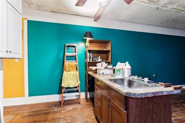 kitchen with dark brown cabinetry, ceiling fan, sink, light hardwood / wood-style floors, and a center island with sink