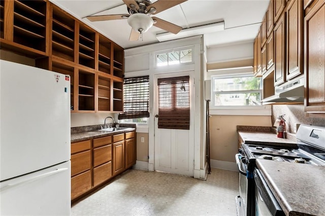 kitchen featuring ceiling fan, white fridge, stainless steel gas range oven, and sink