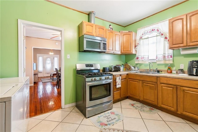 kitchen featuring light wood-type flooring, stainless steel appliances, ceiling fan, sink, and washing machine and clothes dryer